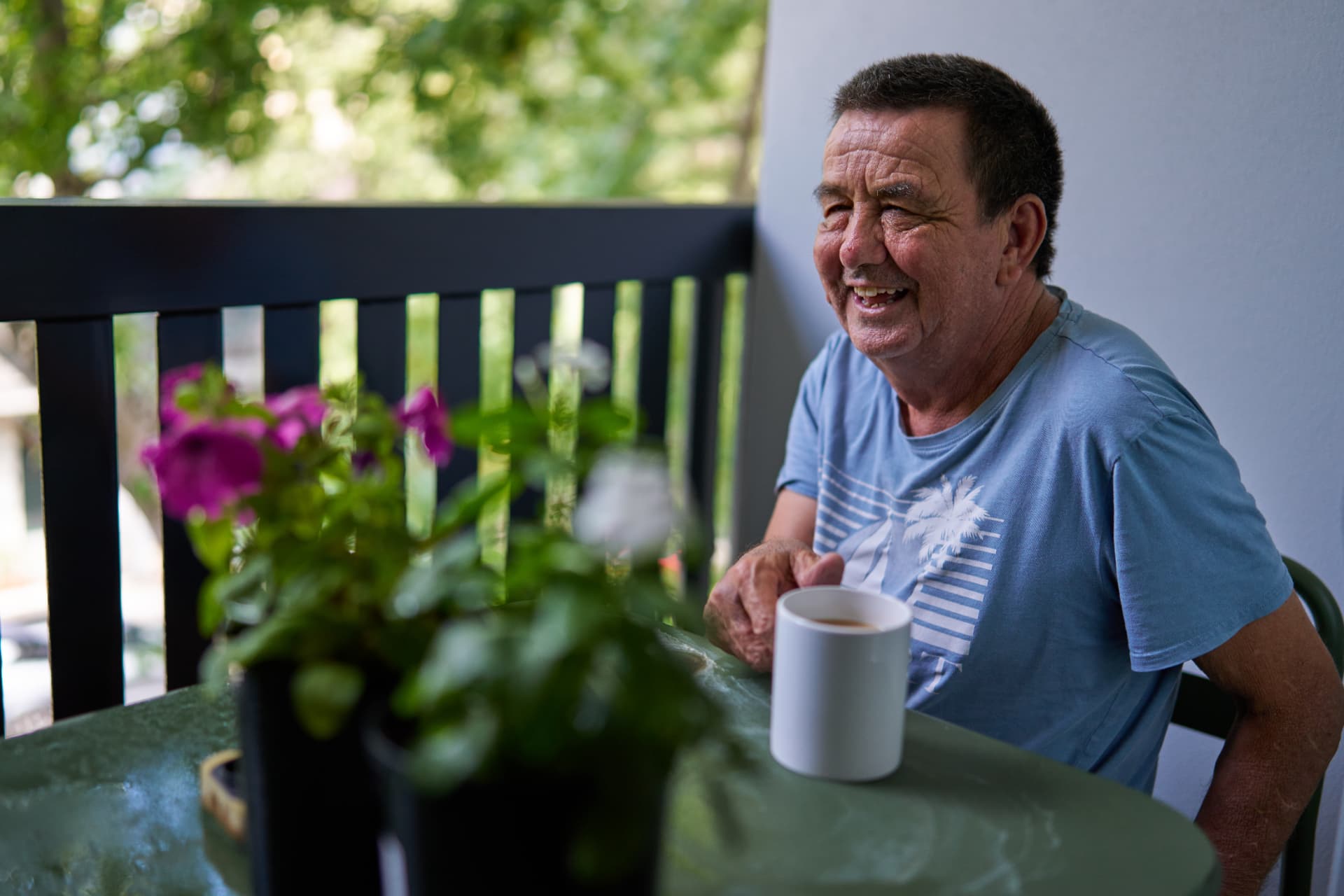 A member and their support worker having a coffee together on the balcony at home.