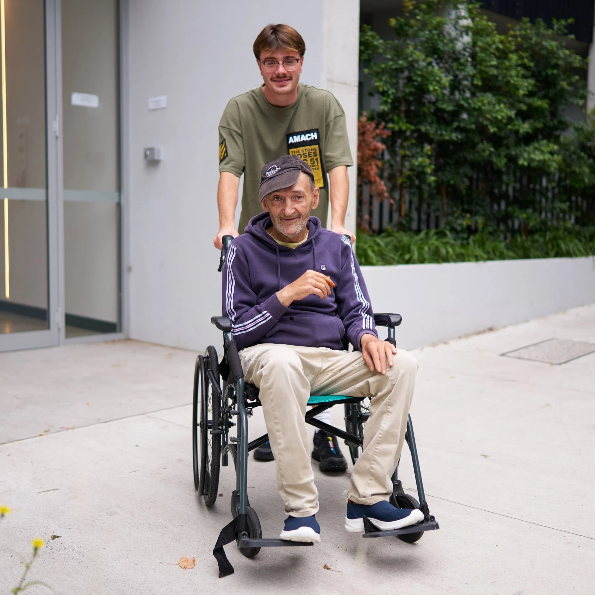 A support worker arriving at the village entrance with a member, heading home together.