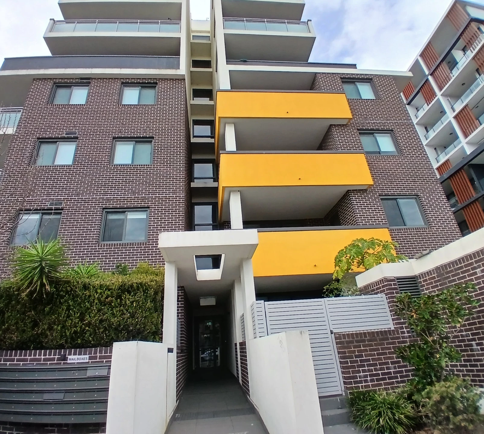 the brick apartment building at Copeland Street, Liverpool, with yellow balconies and a landscaped entry path