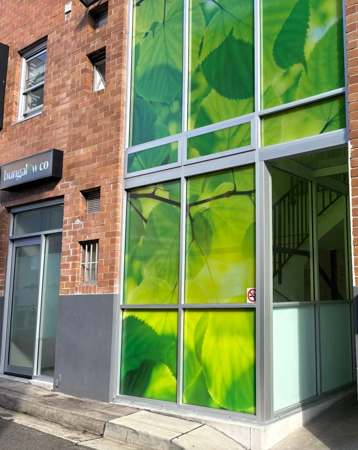 The Bell Lane entrance to the Randwick village, a brick building with a tall green leaf artwork beside the entry door.